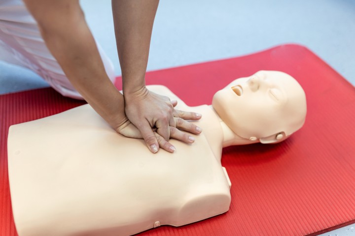 CPR instructor teaching chest compressions on a training manikin